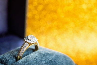 Diamond ring in a box against a yellow background. 