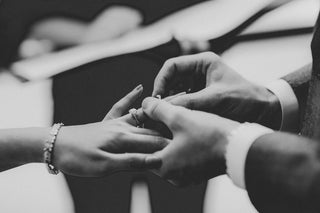 Hand putting on a wedding ring during the wedding ceremony, in black and white